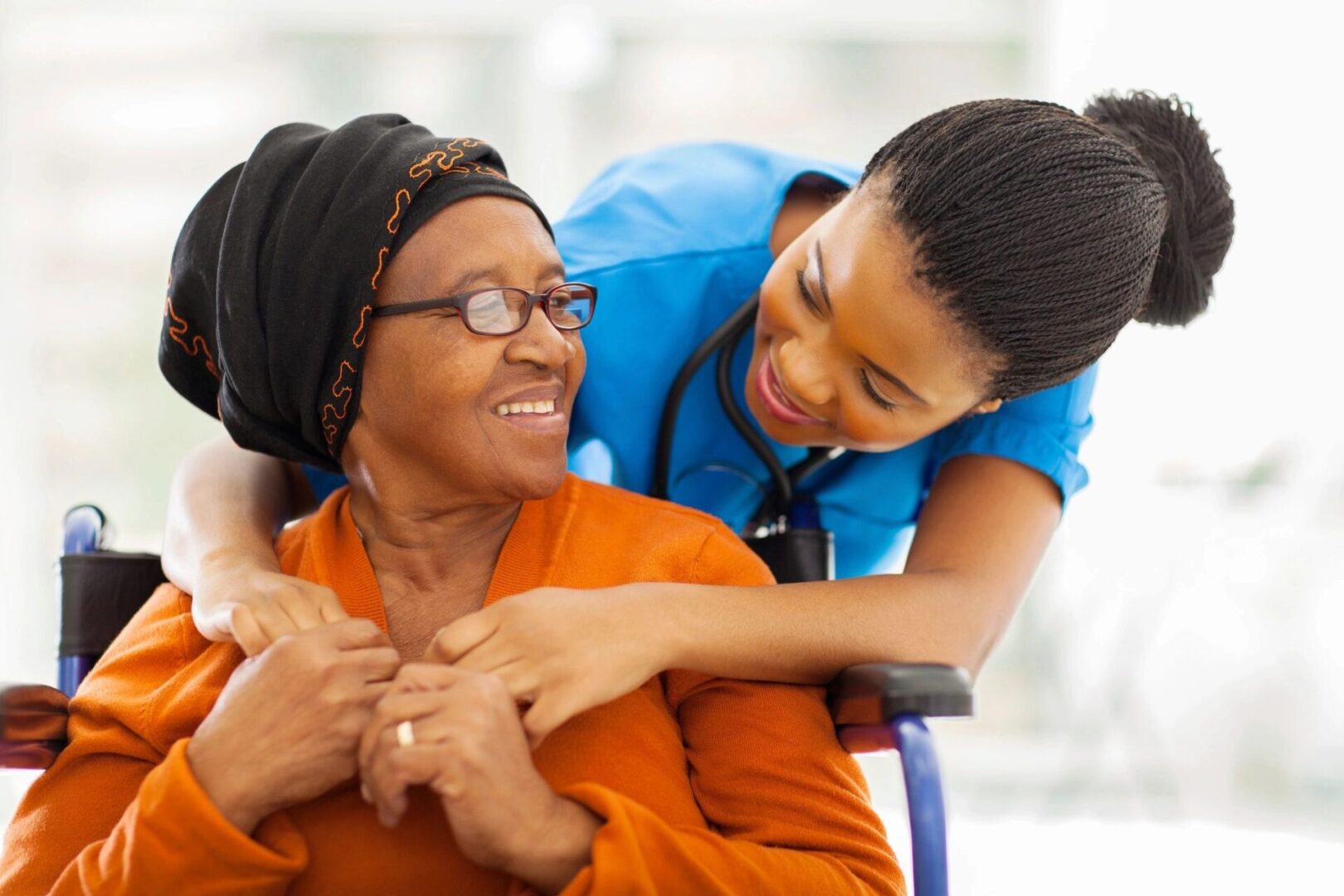 A nurse warmly embraces an elderly woman, sharing a joyful moment.